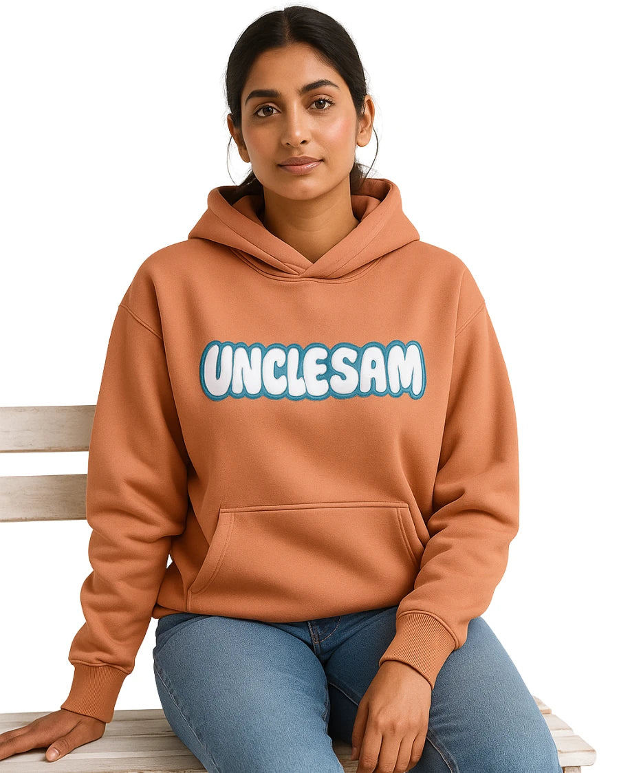Person wearing a brown hoodie with 'UNCLESAM' text, sitting on a wooden bench.