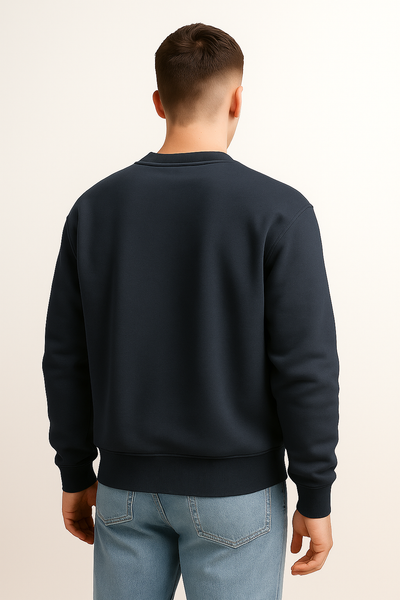 Man wearing a black sweatshirt and light blue jeans on a beige background