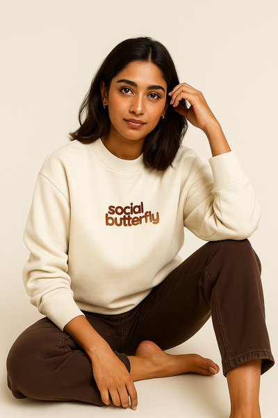 Woman wearing a white sweatshirt with 'social butterfly' text.