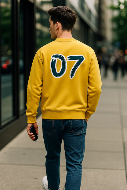 Person wearing a yellow sweatshirt, back profile, with the number 07, walking on a city street.