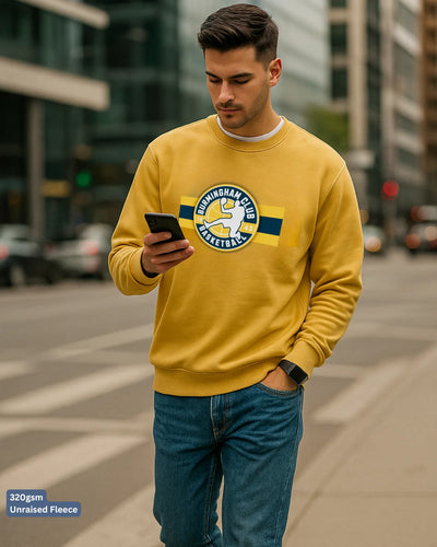 Man wearing a yellow sweatshirt with a logo, standing on a city street.
