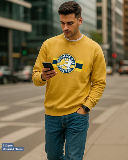 Man wearing a yellow sweatshirt with a logo, standing on a city street.