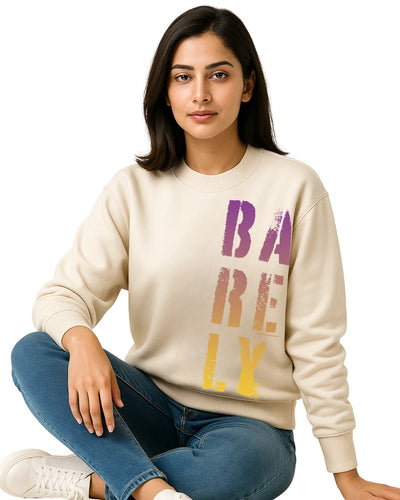 Woman wearing a beige sweatshirt with colorful text sitting on the floor against a white background