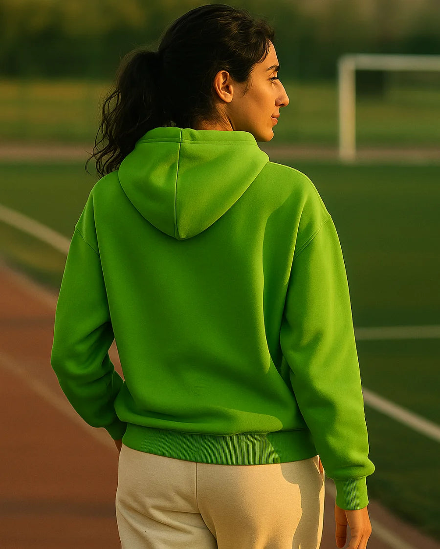 Person wearing a green hoodie on a sports field
