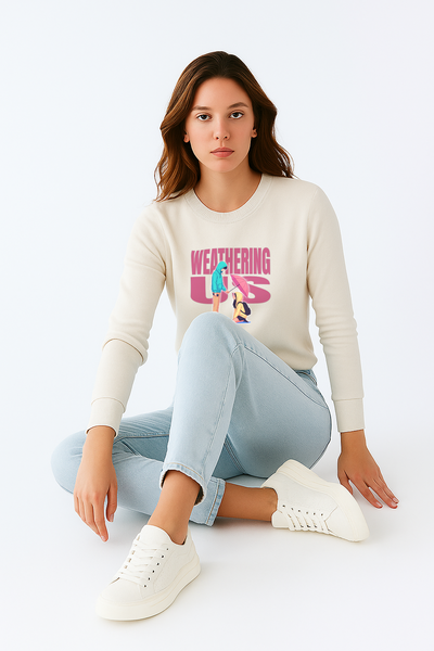 Woman wearing a cream sweater with a graphic design, light blue jeans, and white sneakers on a white background