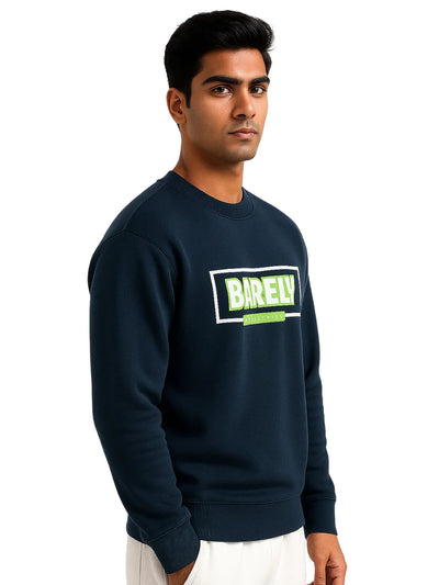 Man wearing a navy blue sweatshirt with 'BARELY' printed on it against a white background