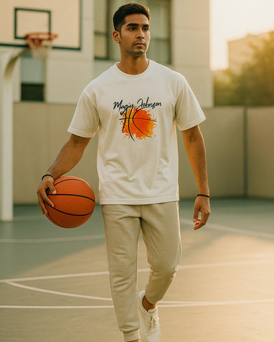 Man holding a basketball on a court wearing a t-shirt with a graphic design.