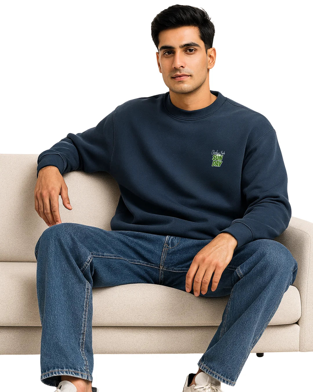 Man wearing a navy blue sweatshirt with a logo, sitting on a beige couch.