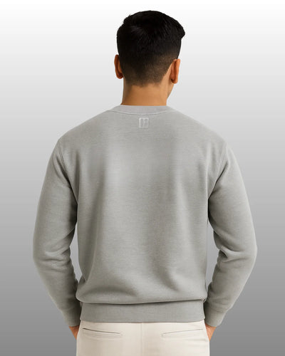 Person wearing a gray sweatshirt with a logo on the back against a plain background