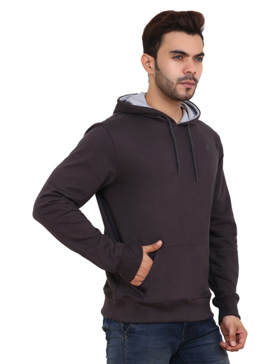 A man wearing a brown hoodie with the hood up, paired with blue jeans.