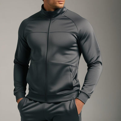 A male model wearing a dark grey tracksuit with a full zipper and standing collar.