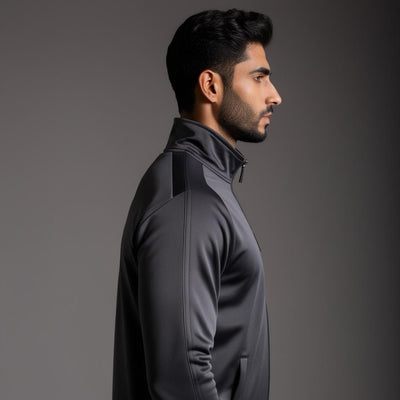 Side View of A male model wearing a dark grey tracksuit with a full zipper and standing collar.